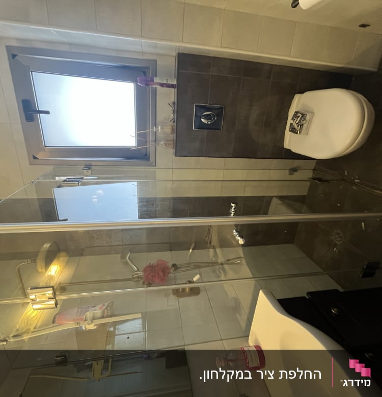 מקלחון זכוכית עם ראש מקלחת ומדף מוצרים